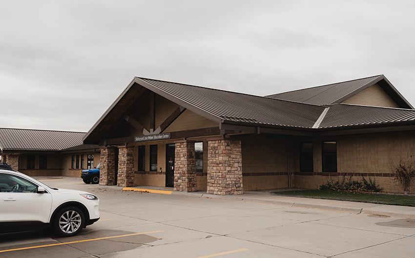 Exterior view of a single-story educational building with stone columns and a covered entrance.