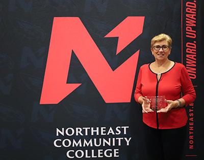 Linda Pelc holding award in front of Northeast Backdrop